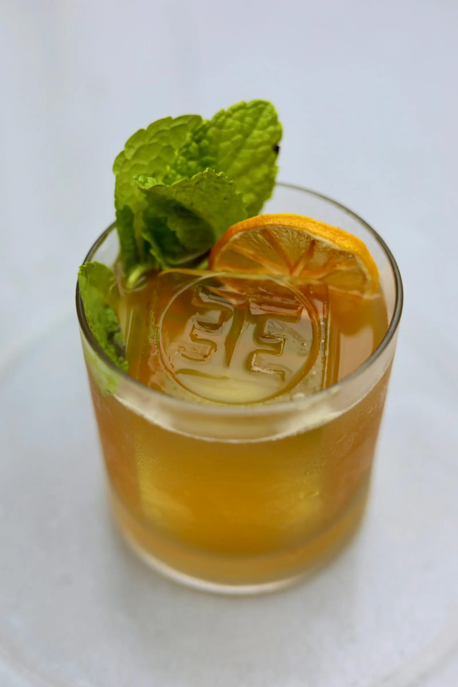 Golden cocktail with mint over embossed ice